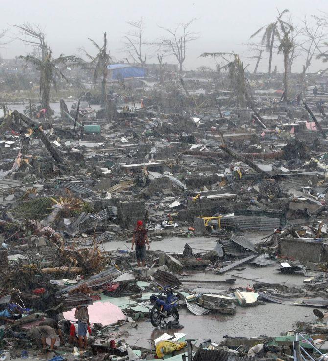 Survivors stand among debris and ruins of houses destroyed after Super Typhoon Haiyan battered Tacloban city in central Philippines