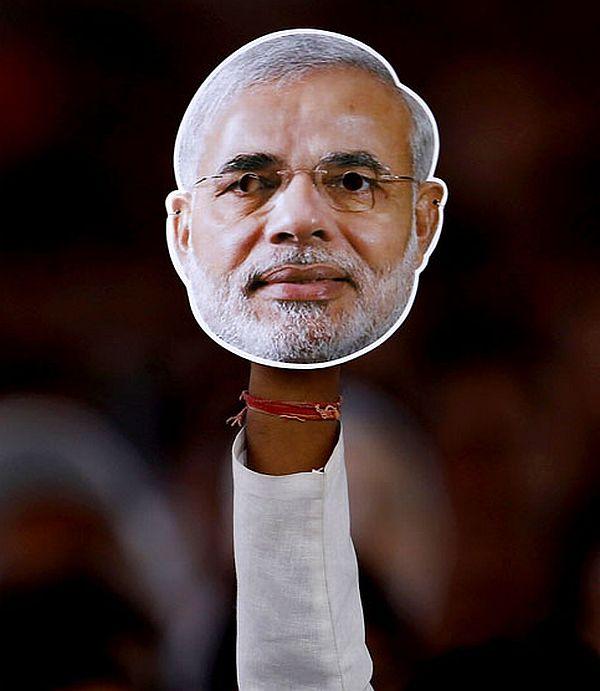 A man holds up a mask of Narendra Modi at a poll rally