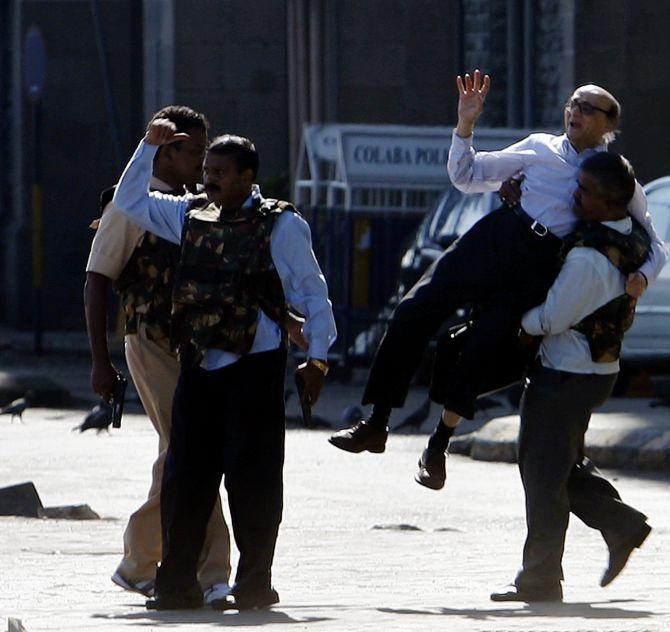 Police escort a stranded guest from Taj hotel in Mumbai during the 26/11 attacks