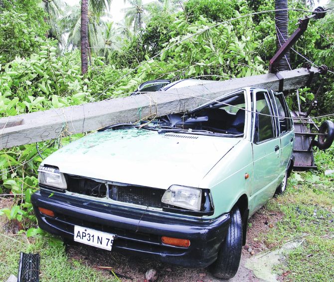 A car is seen damaged by a cyclone-hit fallen electricity pole in East Godavari district of Andhra Pradesh on Friday
