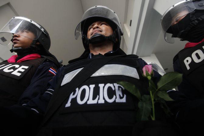 A policeman receives a flower from an anti-government protester as thousands of others gather outside the Department of Special Investigation in Bangkok 