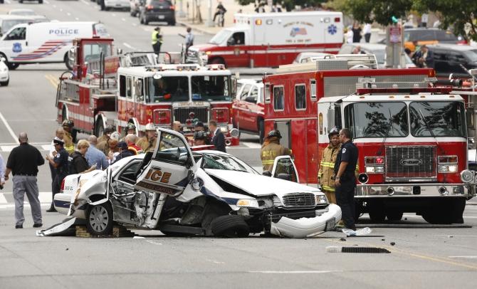 Rescue personnel stand around a smashed US Capitol Police car following a shooting near the Capitol in Washington