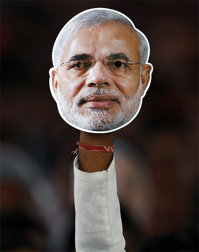 A supporter of BJP holds a mask of Gujarat CM and BJP's prime ministerial candidate Narendra Modi