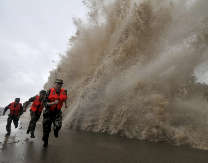 Frontier soldiers run as a storm surge hits the coastline under the influence of Typhoon Fitow in Wenling, Zhejiang province