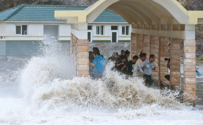 People dodge as a storm surge hits the coastline under the influence of Typhoon Fitow in Wenling, Zhejiang province