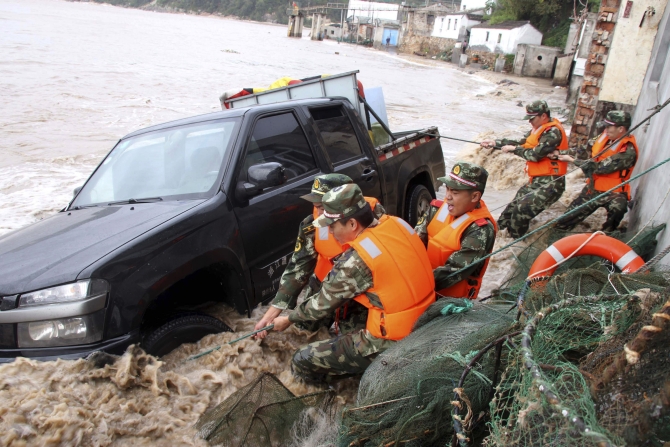 Paramilitary policemen pull up a vehicle overturned by a storm surge near the coastline, under the influence of Typhoon Fitow in Yuhuan, Zhejiang province
