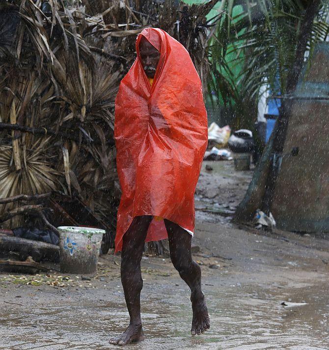 A man covers himself with a plastic sheet during heavy rain brought by Cyclone Phailin as he moves towards a safer place at the village Donkuru in Srikakulam district.