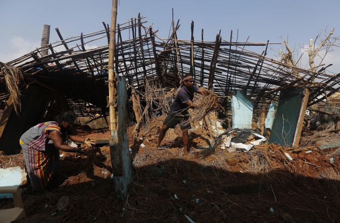 A fisherman and his wife clear the debris from their damaged house after Cyclone Phailin hit Gopalpur village in Ganjam district