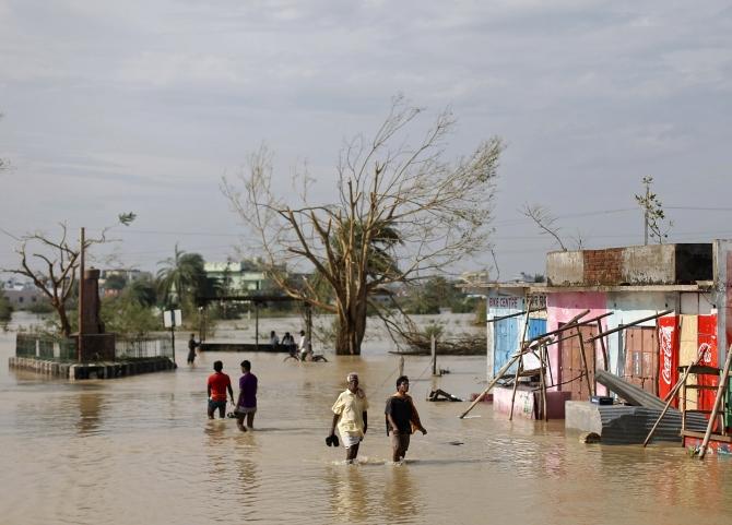 Residents wade through a flooded road after Cyclone Phailin hit Gopalpur in Ganjam district in Odisha