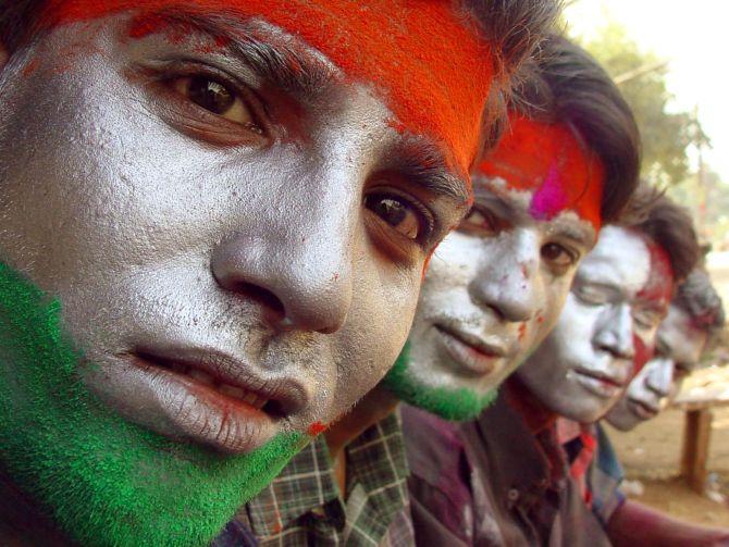 Indians sit with their faces painted with the colours of the Indian national flag as they celebrate Holi in the central Indian city of Bhopal