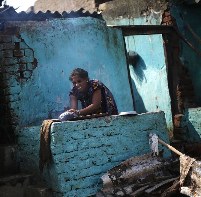 A woman cooks food outside her partially damaged house at the cyclone-hit Gopalpur village, in Ganjam district