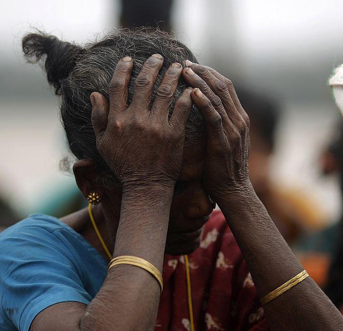 A woman holds her head after Cyclone Phailin hit Sunapur village in Ganjam