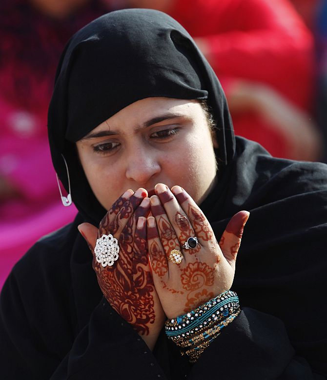 A Muslim woman with henna tattoos on her hands, attends a mass prayer for Eid al-Adha