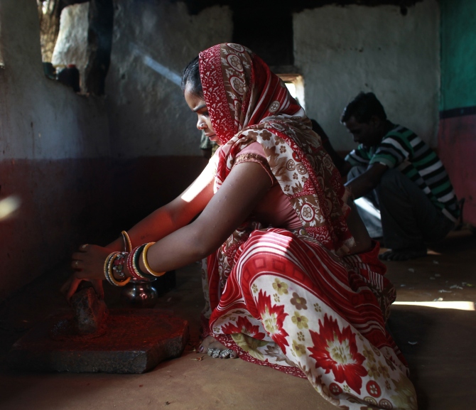 Krishna, 13, grinds spices inside the kitchen at her house in a village