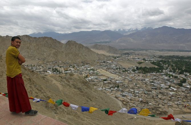 A Buddhist monk stands on a pathway overlooking Leh city in Ladakh.