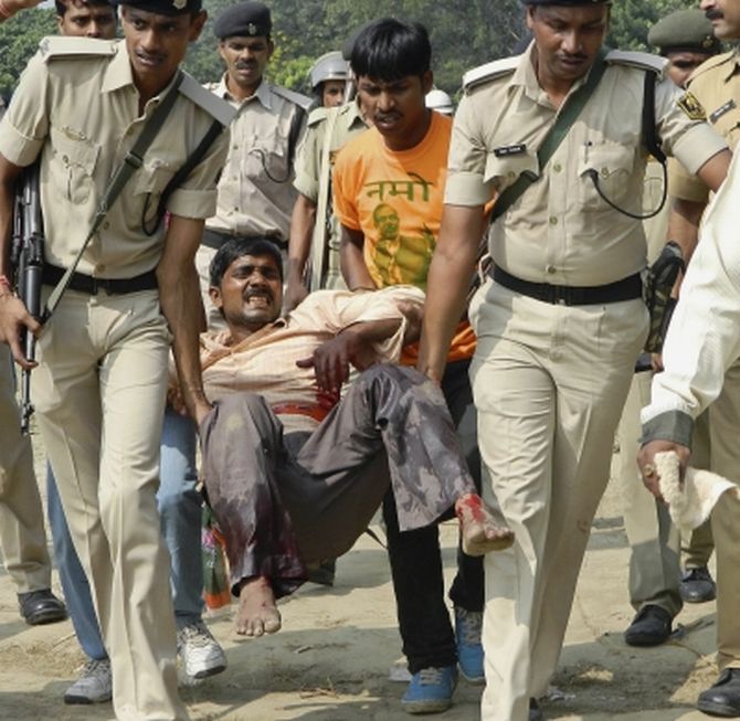 Police personnel carrying an injured man after serial blasts rocked Patna's Gandhi maidan during Modi's rally on Sunday