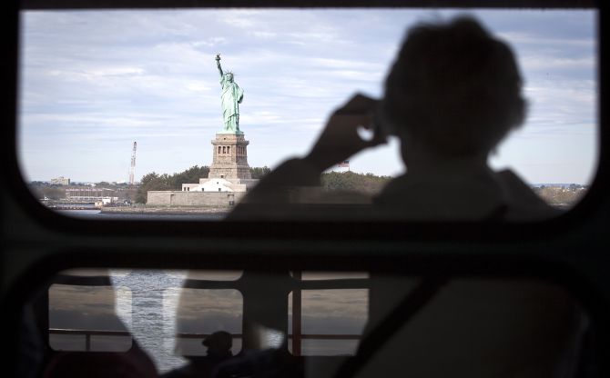The Statue of Liberty is pictured from the Staten Island Ferry as people are reflected in windows in New York