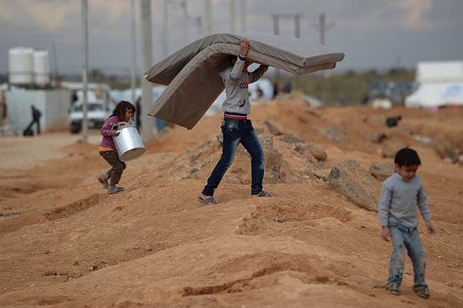 A boy carries a mattress as Syrian refugees go about their daily business in the Za'atari refugee camp in Mafraq, Jordan