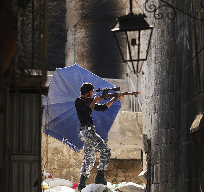 A Free Syrian Army fighter aims his weapon as he takes a defensive position in the old city of Aleppo