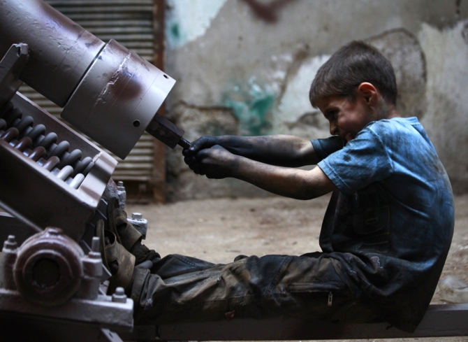 Issa, 10 years old, fixes a mortar launcher in a weapons factory of the Free Syrian Army in Aleppo