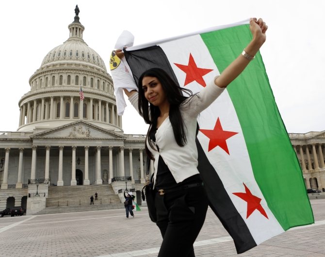 An anti-Assad protester carries the Syrian freedom flag in front of the US Capitol in Washington