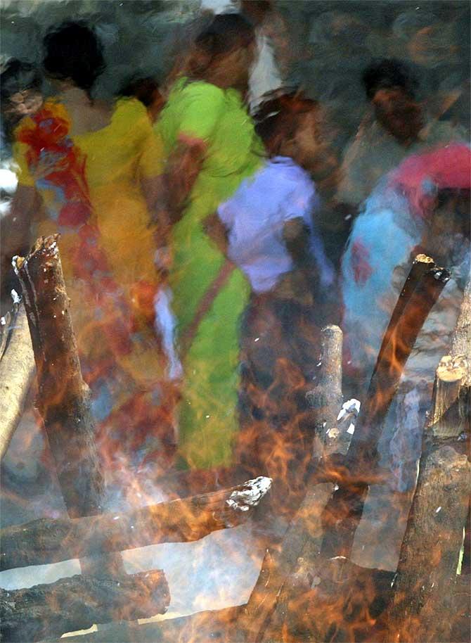 Family members stand near the pyre of a victim of the Hyderabad blast