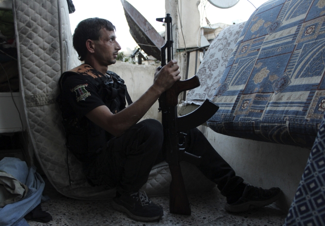 A Free Syrian Army fighter carries his weapon as he takes a position in Aleppo's Al-Ezaa neighbourhood