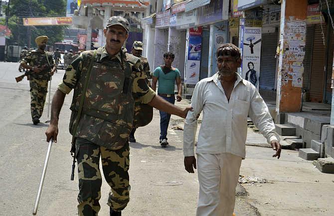 Security personnel detain two men for questioning during a curfew in Muzaffarnagar after the communal violence in September 2013.