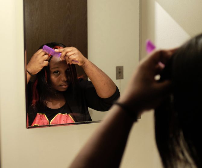 Former adopted child Quita Puchalla fixes her hair in her apartment in Milwaukee, Wisconsin. Puchalla, now 21, was moved from home to home as an adopted child from Liberia and now lives on her own and is going to school. 