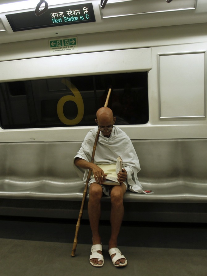 Mahesh Chaturvedi, 63, who dresses up like Mahatma Gandhi, reads a copy of the Bhagavad-Gita in the Delhi metro train.