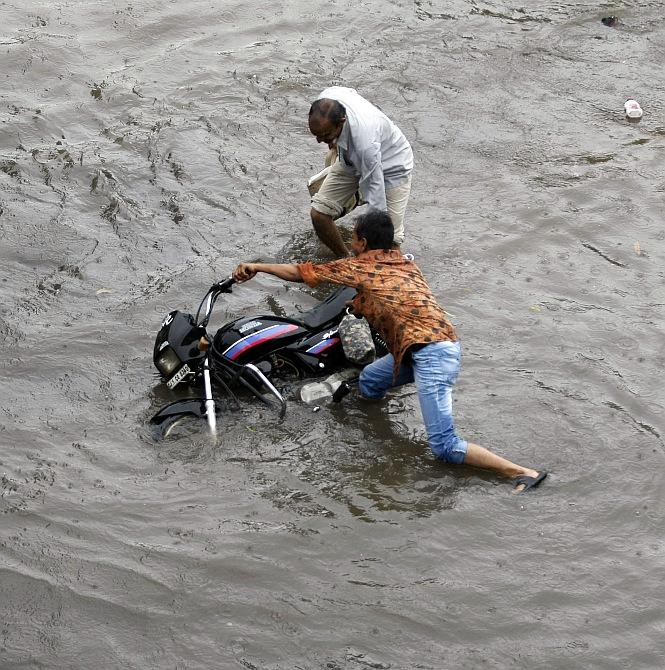 A man tries to right his motorcycle after it skidded in a flooded street after heavy rains in Ahmedabad