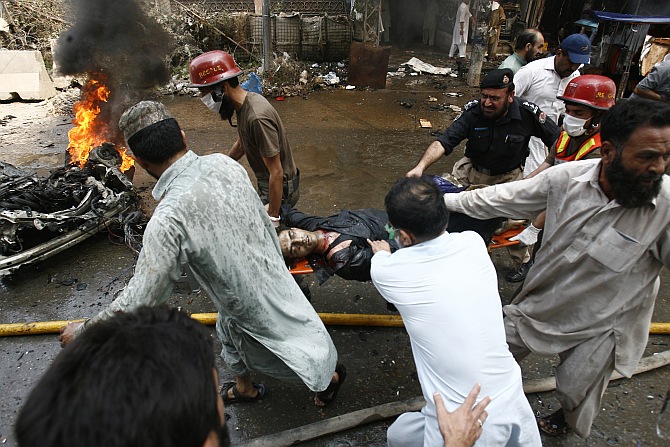 Security officials, rescue workers and residents gather at the site of a bomb attack in Peshawar