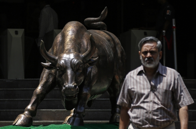 A bronze bull sculpture is seen as an employee walks out of the Bombay Stock Exchange) building in Mumbai.