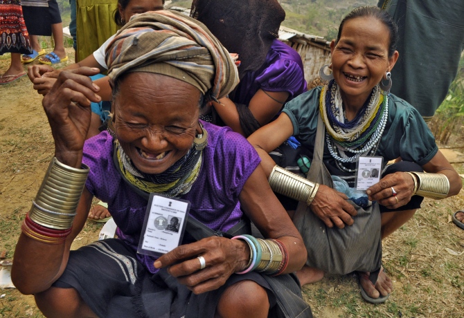 Reang refugees wearing traditional ornaments display their voter cards as they wait to cast their ballots at Thamsapara relief camp in Tripura.