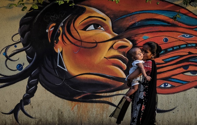 A mother kisses her child as she walks past graffiti in Mumbai.