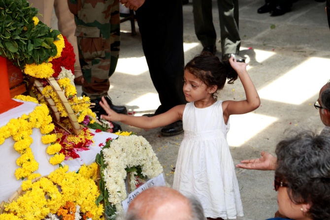 Arshea, 3, the major's daughter, stands near her father's coffin 