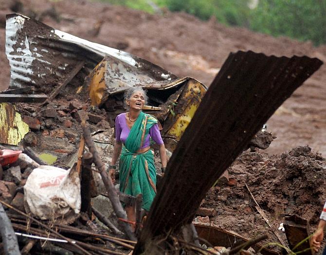 A villager search for family members among the debris of her house at the site of a landslide in Malin village, in Maharashtra on Wednesday