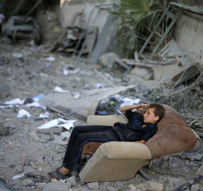 A Palestinian boy sits on a sofa outside his family's house, which witnesses said was damaged in an Israeli air strike, in Gaza City. 