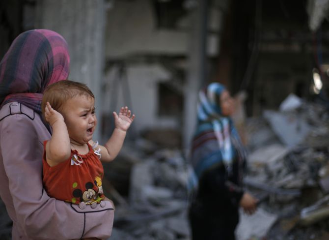 A Palestinian woman holds her daughter as she looks at the wreckage of her house in Beit Hanoun town, which witnesses said was heavily hit by Israeli shelling and air strikes during Israeli offensive, in the northern Gaza Strip.