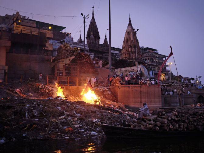 People watch as pyres burn at a cremation ground on the banks of river Ganges in Varanasi.