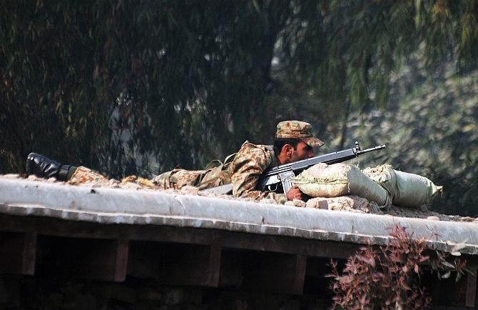 Image: A Pakistani soldier takes up a position above a road near the school. Photograph: Khuram Parvez/Reuters