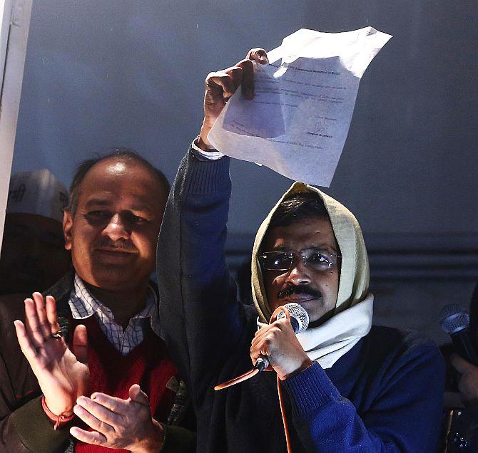 Delhi's Chief Minister Arvind Kejriwal shows his resignation to his supporters while addressing them from his party headquarters in New Delhi on Friday