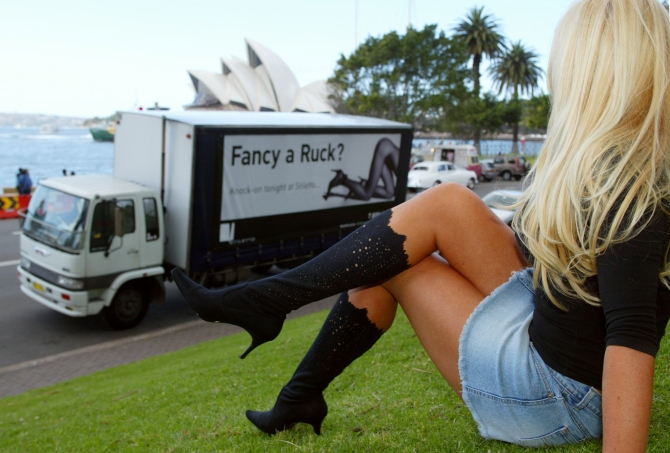 A brothel promotions team member poses for a photograph at Circular Quay in Sydney before a truck bearing the words Fancy a Ruck sets off on a drive through city streets to advertise the brothel.