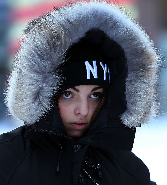 A woman walks through a cold and snow covered Times Square following a snow storm that left up to 8 inches of snow