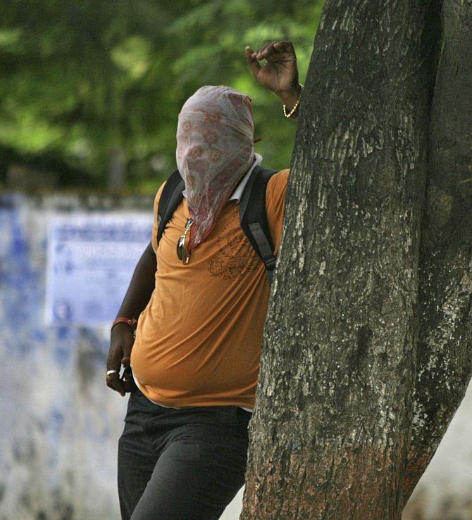 An arsonist hides behind the tree to to avoid tear gas smoke thrown by the riot police.