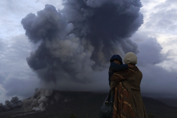 A mother holds her son as they watch the eruption of Mount Sinabung at Berastepu village in Karo district, Indonesia's North Sumatra province.