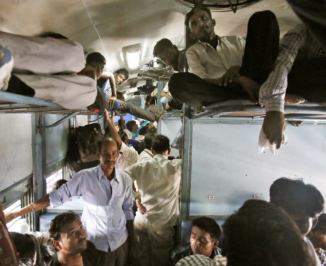 Passengers sit inside a crowded stationary train at a railway station in New Delhi