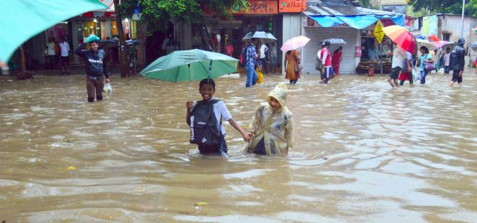 Little children wade through knee-high water after rains lashed the city.