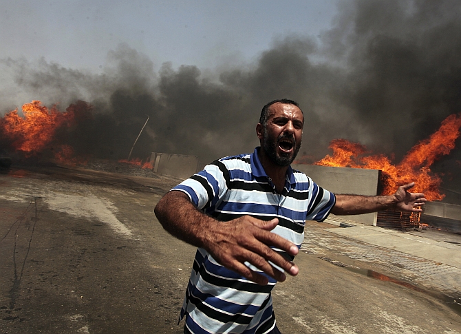 A Palestinian reacts in front of a fire which police said was caused by an Israeli tank shelling in the industrial area in the east of Gaza Cit