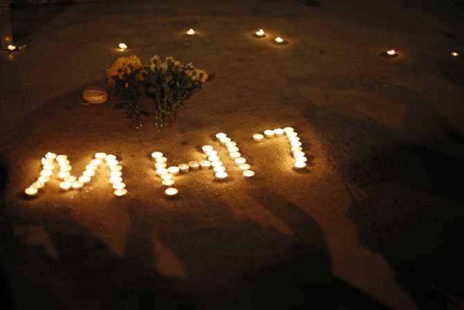 People take pictures of an MH17 sign during a candlelight vigil in Kuala Lumpur 